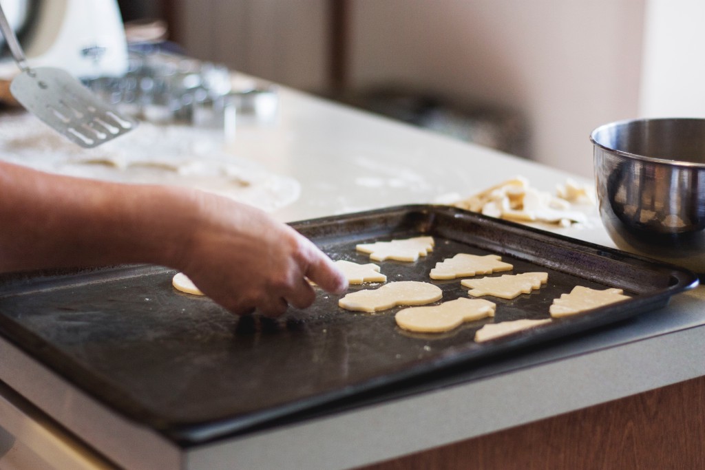 mani che sistemamo dei biscotti da cuocere su una teglia da forno 